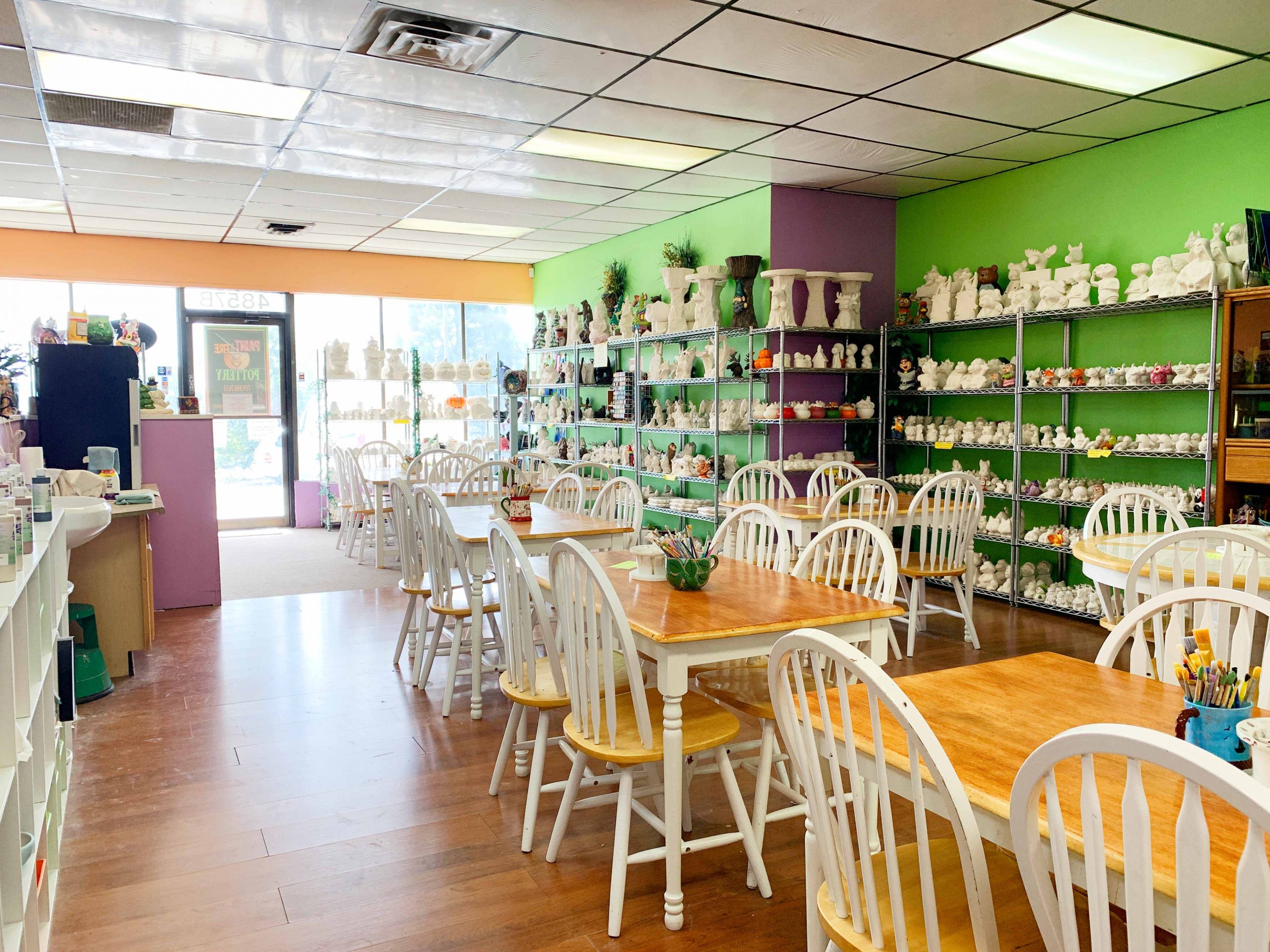 Inside Paint & Fire Pottery studio — colorful walls, painting tables with brushes, and shelves filled with ceramic pieces ready to paint